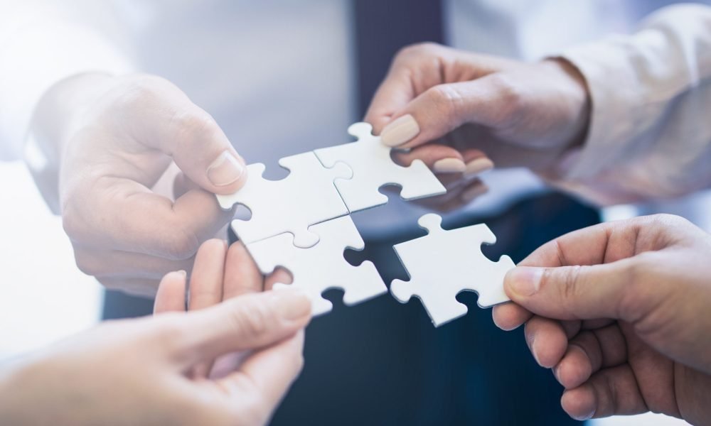 A group of business people assembling jigsaw puzzle. The concept of cooperation, teamwork, help and support in business.