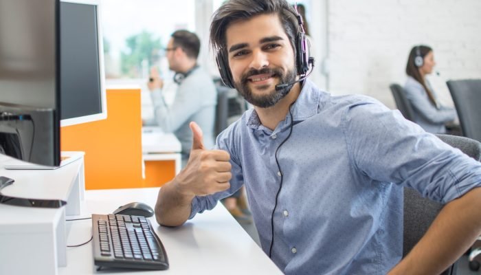 Happy male customer service operator showing thumb up in office.